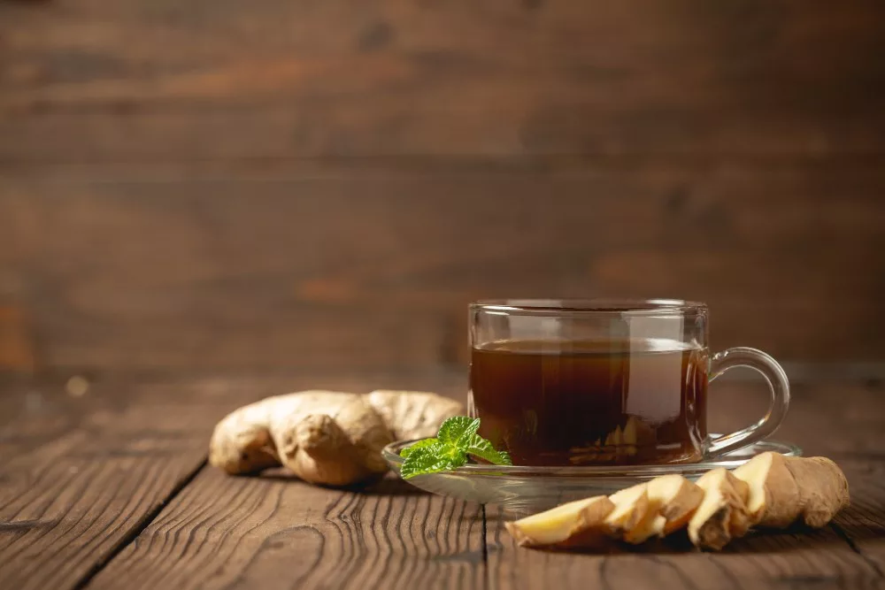 hot ginger juice and ginger sliced on wooden table