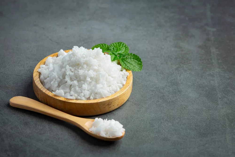 Image of salt in wooden small plate with a wooden spoon beside