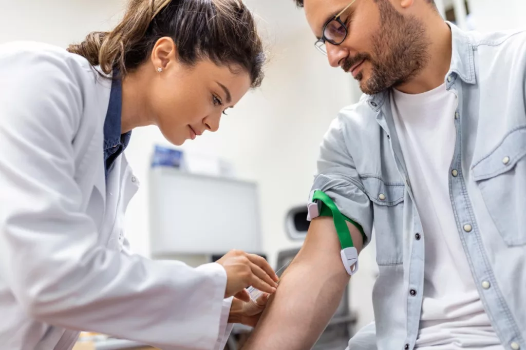 Image of a phlebotomist collecting blood sample from patient in lab